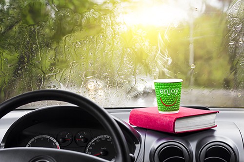 Rainy day in the car window with a glass of hot coffee and a book | Pass the Time on Autonomous Drives