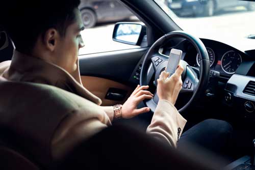 business man in expensive coat texting and driving | New Texting Law in Colorado Raises Concerns