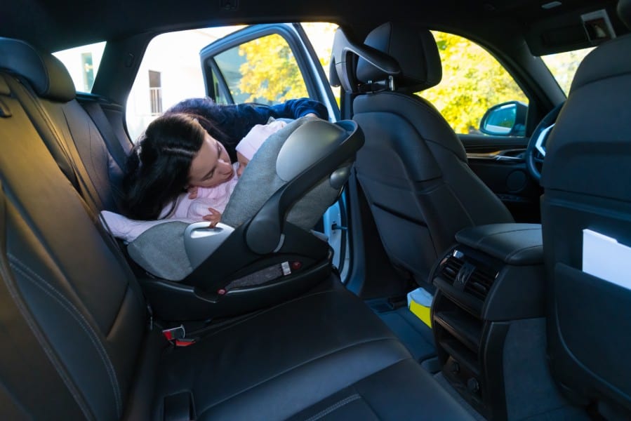 lady putting her baby at the back seat | safest seat in a car accident